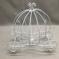 a white metal carriage with wheels on a gray background in the shape of a birdcage