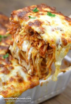 a piece of lasagna being lifted from a casserole dish with cheese