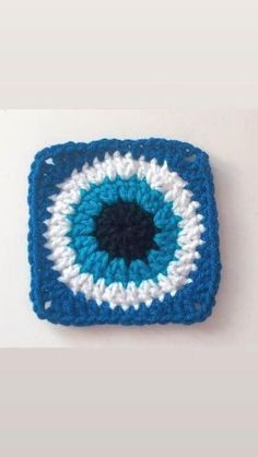 a crocheted square with an eye on the center is shown in blue and white