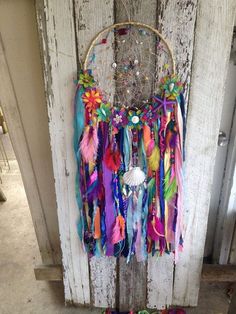 a colorful dream catcher hanging on the side of a wooden door with beads and feathers