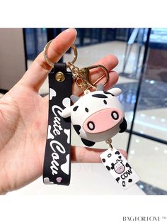 a hand holding a cow keychain with a black and white tag on it