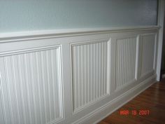 an empty room with white paneling on the wall and wood floors in front of it