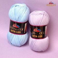 two skeins of yarn sitting next to each other on a purple surface with the words himalaya written in black