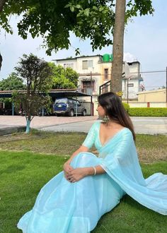 a woman in a blue dress sitting on the grass