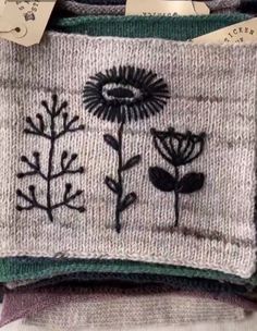 some flowers and leaves are embroidered on sweaters with tags attached to them as if they were made from wool