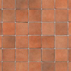 a close up view of a red brick wall with small square tiles on the bottom