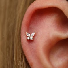 a woman's ear is adorned with a tiny diamond butterfly