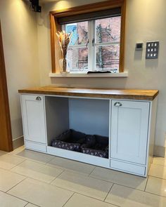 a dog bed under a window in a room with tile flooring and white walls