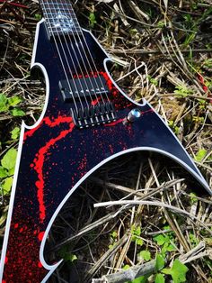 an electric guitar laying on the ground with red paint splatters all over it