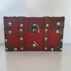 a red leather box with brass hardwares on the front and sides is sitting on a white surface