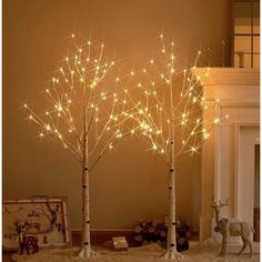 three lighted birch trees in front of a fireplace