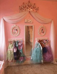 a room with pink walls and lots of clothes hanging on the rack in front of it