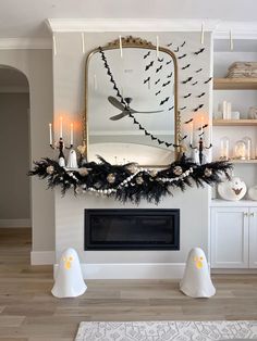 a living room decorated for halloween with white and black decorations on the fireplace mantel