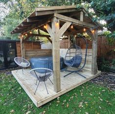 a wooden gazebo with two chairs and a hot tub