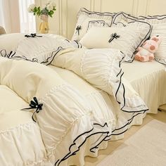 a bed with white sheets and black bows on the pillow cases, along with pillows