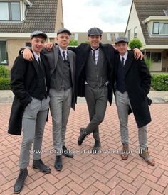 three men in suits and hats are posing for a photo outside their homes, one is wearing a hat