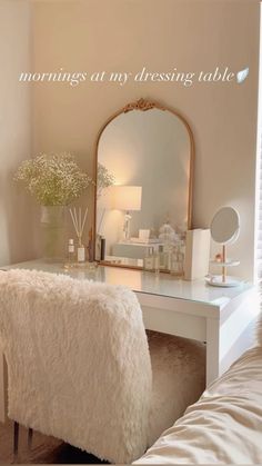 a white desk with a mirror and some flowers