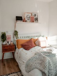 a white bed topped with lots of pillows and blankets