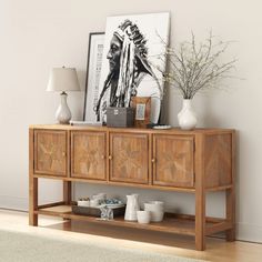 a wooden table with vases and other items on it next to a white wall