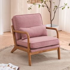 a pink chair sitting on top of a rug in front of a tree and window