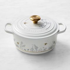 a white casserole with gold lid and flowers on it