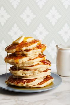 a stack of pancakes with syrup being poured on top