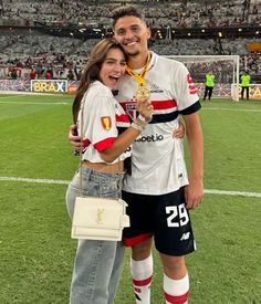 a man and woman standing on top of a soccer field holding an award medal in their hands