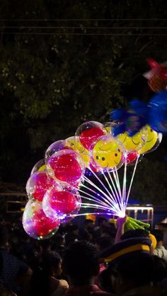 a bunch of balloons that are floating in the air with faces on them at night