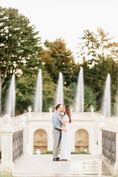 an engaged couple standing in front of a fountain