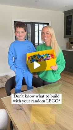 a man and woman standing next to each other holding a lego box