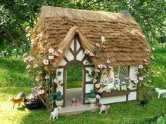 a small house with flowers and plants on the roof