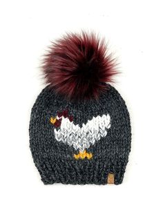 a knitted hat with a red pom - pom on the top and an eagle