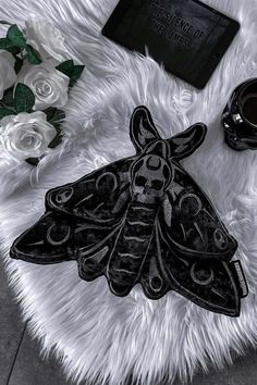 a black and white image of a moth on a furry rug next to some flowers