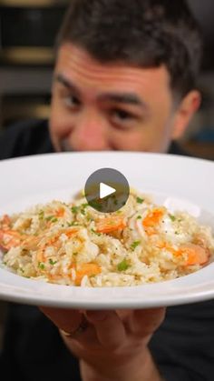 a man holding a white plate with rice and carrots on it in front of his face