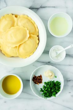 the ingredients for this dish are in bowls on the marble countertop, along with two cups and spoons