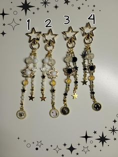 four different charms are hanging on a white surface with black stars and confetti