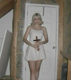 a woman standing in front of a door with a cross on it's chest