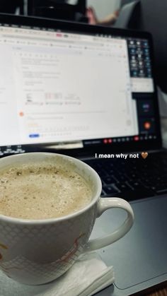 a cup of coffee sitting on top of a table next to a laptop