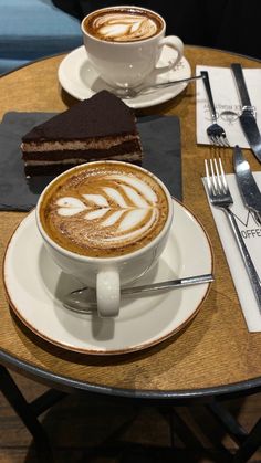 there is a cup of coffee and a slice of cake on the table with silverware