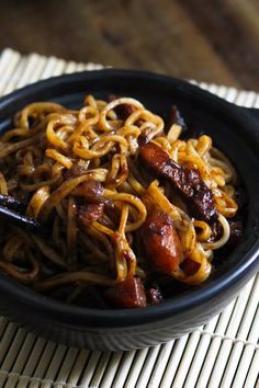 a black bowl filled with noodles and meat