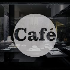 the word cafe is written in black and white on a circular glass window behind it