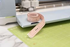 a tape measure is on top of a cutting board next to a sewing machine and ruler