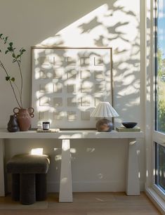 a white table with two vases and a lamp on it next to a window