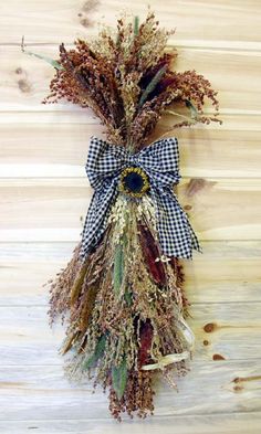 dried flowers are tied to the side of a wooden wall with a blue and white checkered bow