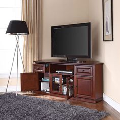 a flat screen tv sitting on top of a wooden entertainment center next to a lamp