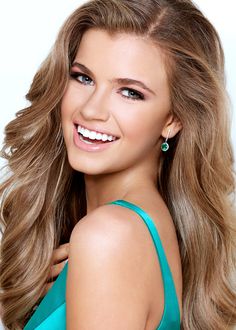 a beautiful young woman with long blonde hair and blue eyeshadow smiling at the camera