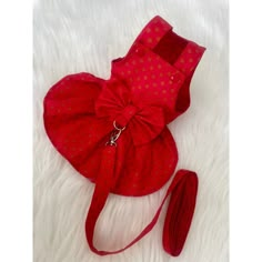 a red purse with a bow on it sitting on top of a white fur rug