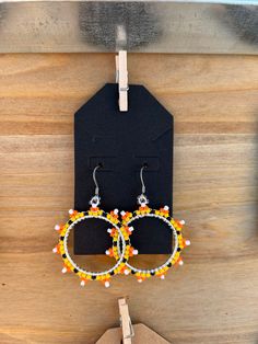 two pairs of earrings hanging from a hook on a wooden board with a tag attached to it