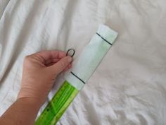 a person is holding scissors and paper on top of a sheet of white fabric with green stems sticking out of it