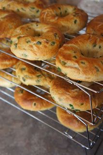 several trays of bagels are cooling on the rack, ready to be eaten